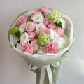Bouquet of pink, white, and green flowers wrapped in paper with a ribbon on a light gray background