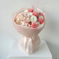 Bouquet of flowers in a pink wrap on a white pedestal against a light gray background