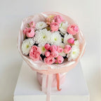 Bouquet of pink and white flowers wrapped in cellophane with a ribbon on a light background