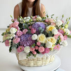 Woman holding a large basket of pastel flowers on a white background