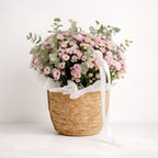Basket of pink flowers with greenery on a white background