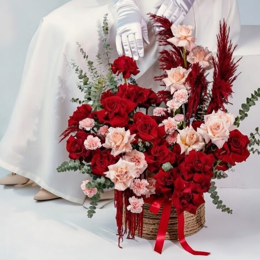Bouquet of red and pink flowers with a white dress and gloves on a light gray background